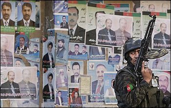 An Afghan police stands guard in front of presidential election posters on the street in Kabul, Wednesday, Aug. 19, 2009. Later, gunfire and explosions reverberated through the heart of the Afghan capital Wednesday on the eve of the presidential election after three militants with AK-47s rifles and hand grenades overran a bank. Police stormed the building and killed the three insurgents, officials said. (AP Photo/Kevin Frayer)