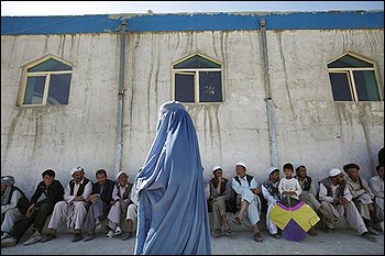 An Afghan woman voter walks past male voters lining up to cast their ballots, as she heads towards the women's side of a mosque made into a polling station in Kabul on Thursday Aug. 20, 2009. Afghans voted under the shadow of Taliban threats of violence Thursday to choose their next president for a nation plagued by armed insurgency, drugs, corruption and a feeble government nearly eight years after the U.S.-led invasion. (AP Photo/David Guttenfelder)