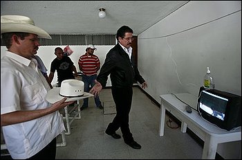 Honduras' ousted President Manuel Zelaya stretches his arm to get his hat while watching a protest of his supporters on a TV at the Brazilian embassy in Tegucigalpa, Thursday, Oct. 29, 2009. Honduras' opposing political factions resumed talks Thursday and expressed hope that a deal could be reached soon to end the power crisis that has paralyzed the country since a coup four months ago. (AP Photo/Esteban Felix)